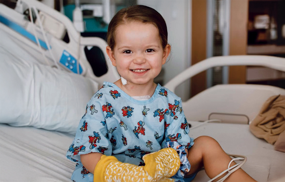 A child named Brooklyn in hospital gown sitting on bed