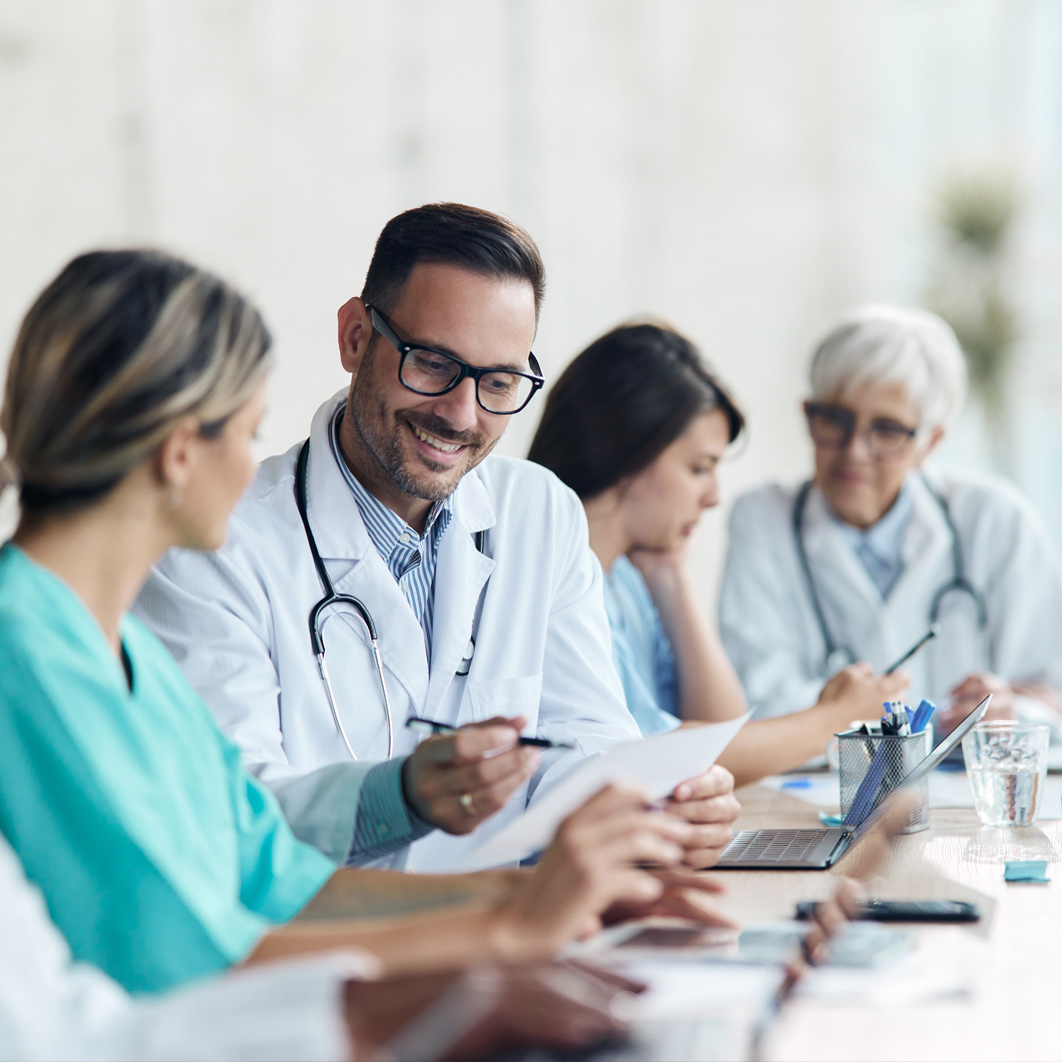 Group of medical staff meeting at a conference table with office supplies.