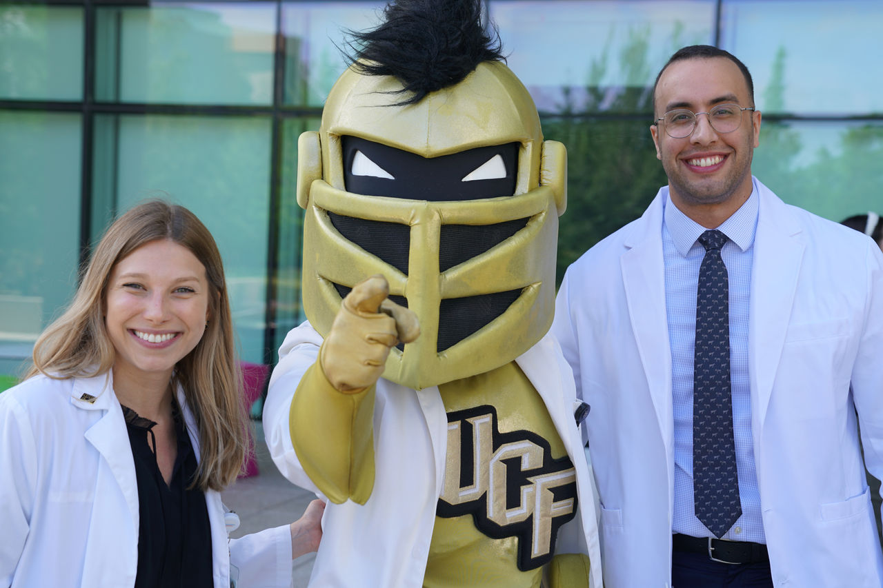Two providers standing with the UCF mascot.