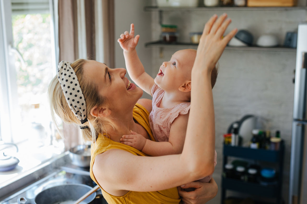 Happy mother and baby point towards the ceiling.