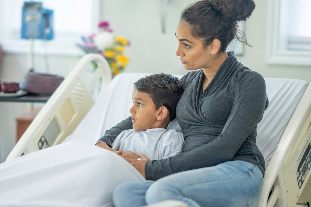 Mom comforting son in hospital bed