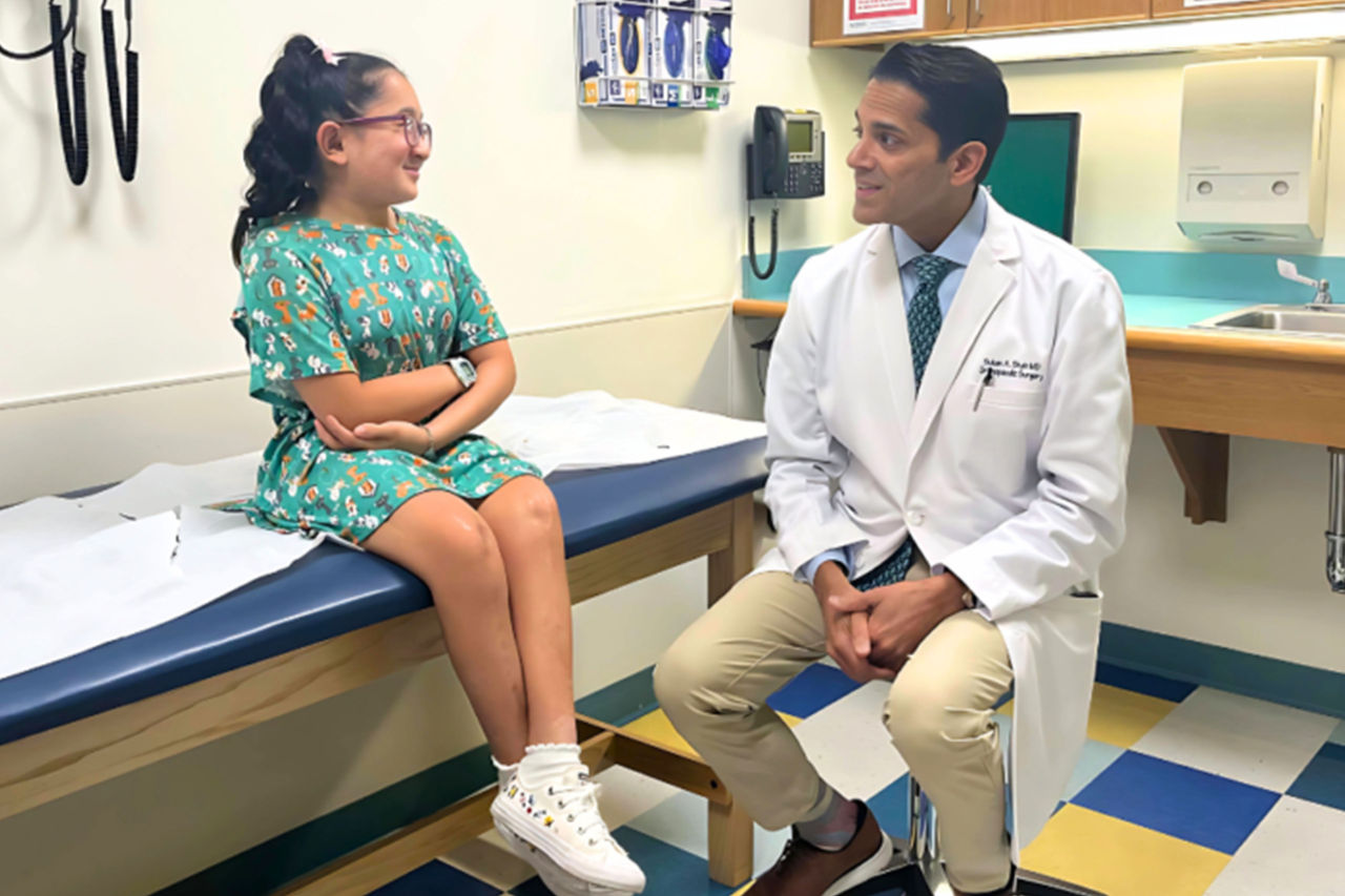 Dr Shah speaking with a young patient in an examination room