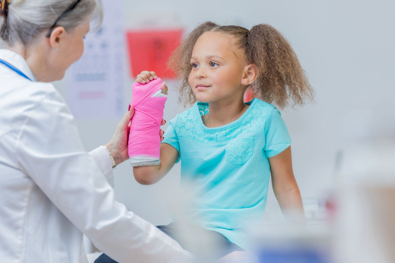 Child with pink arm cast with doctor