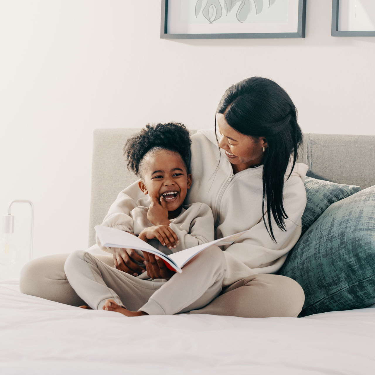 A mother and daughter laughing while reading together.