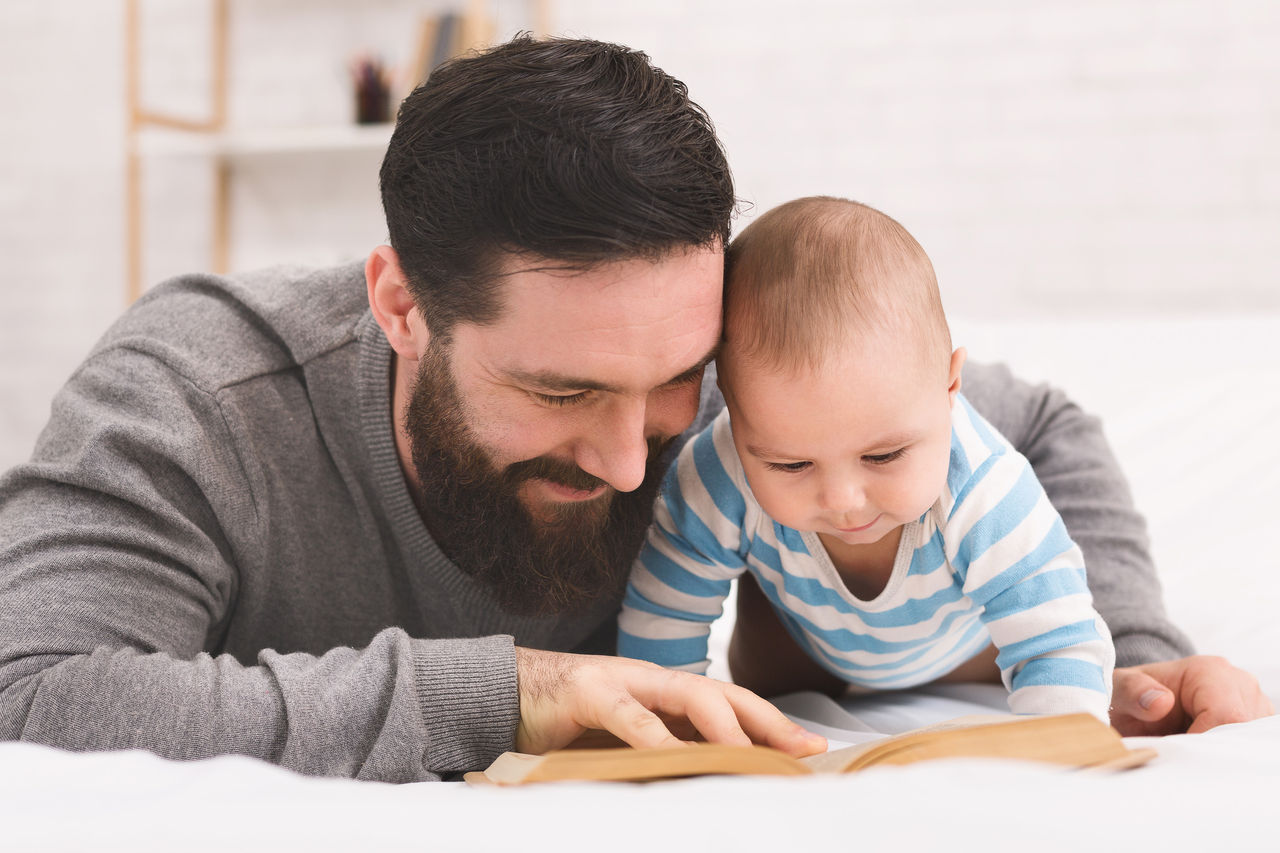 A father snuggled up with his infant child while they read together.