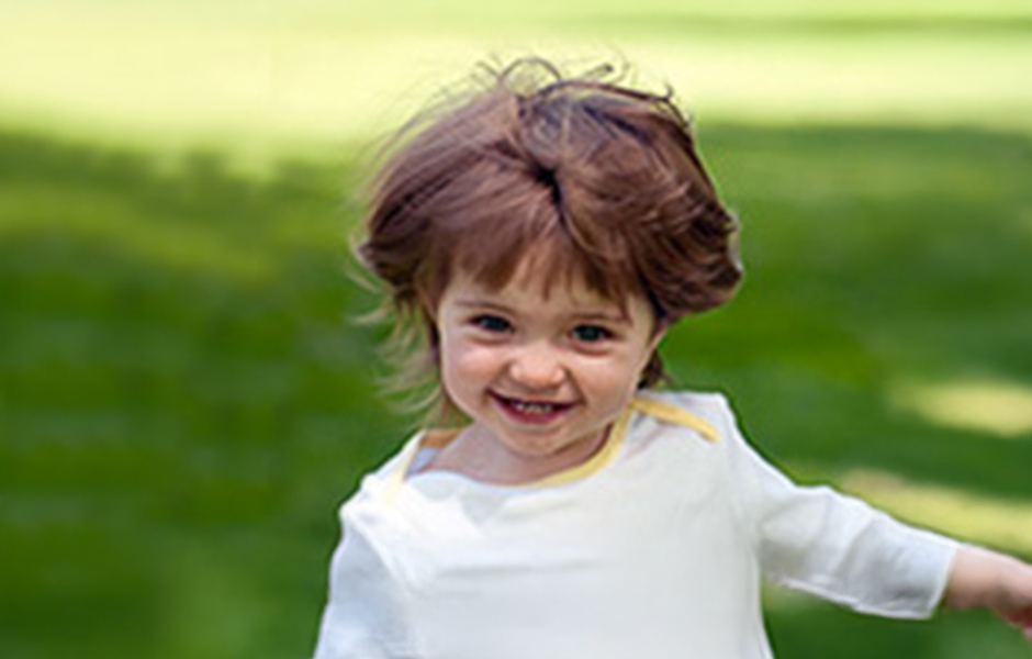 Photo of Ayla smiling at the camera outdoor playing on the grass